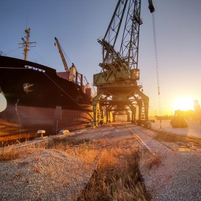 big cargo ship bulk carrier is loaded with grain of wheat in port at sunset